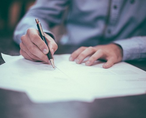 man schrijft met pen op papier